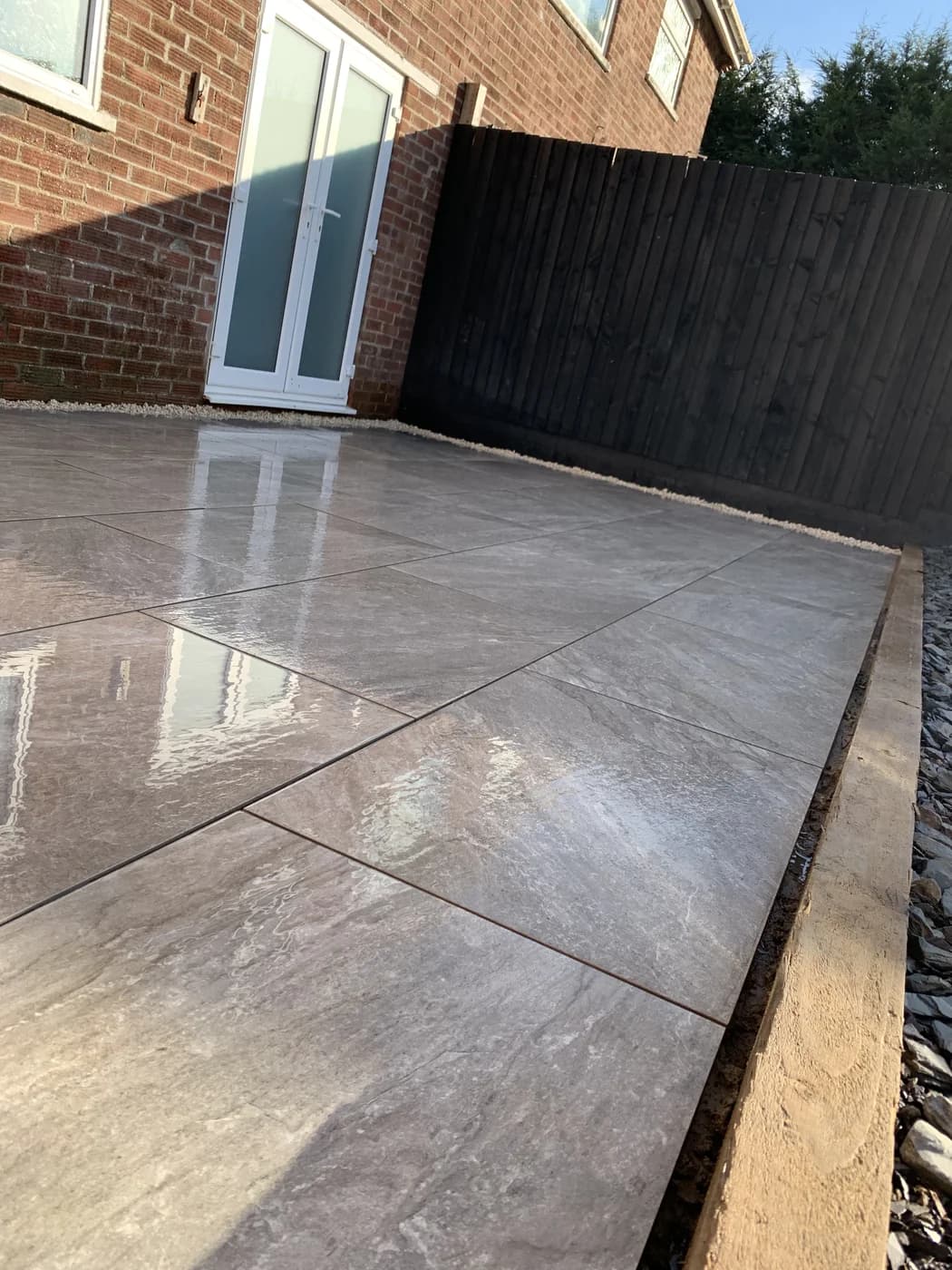 Porcelain patio installation beside a dark fence in Bridgend by HJB