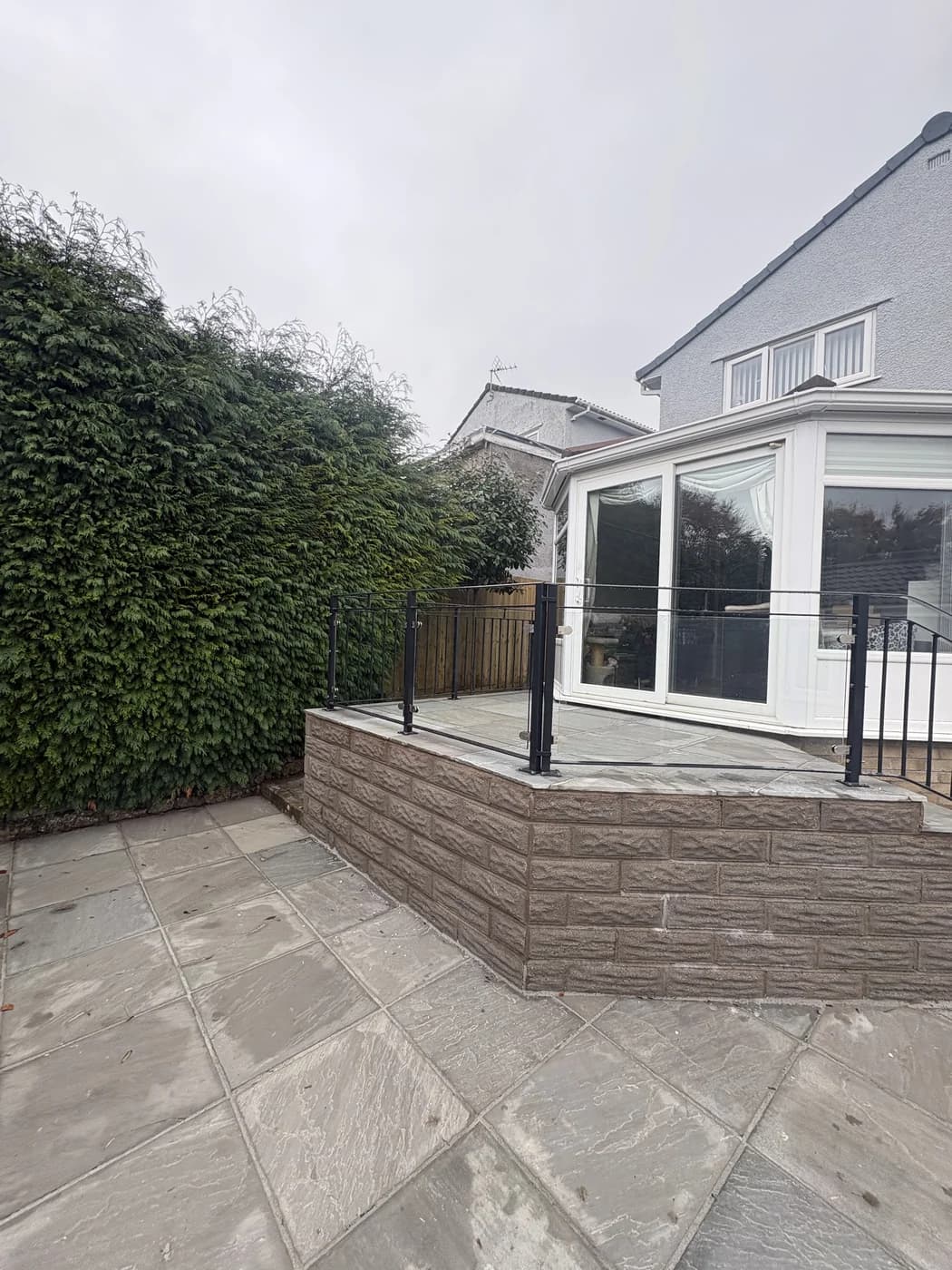 Sandstone patio with steps beside a conservatory in Maesteg by HJB