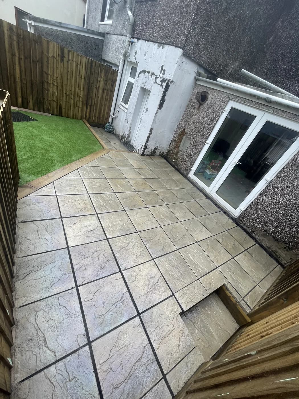 Courtyard patio with artificial grass by the rear door in Ogmore Vale by HJB
