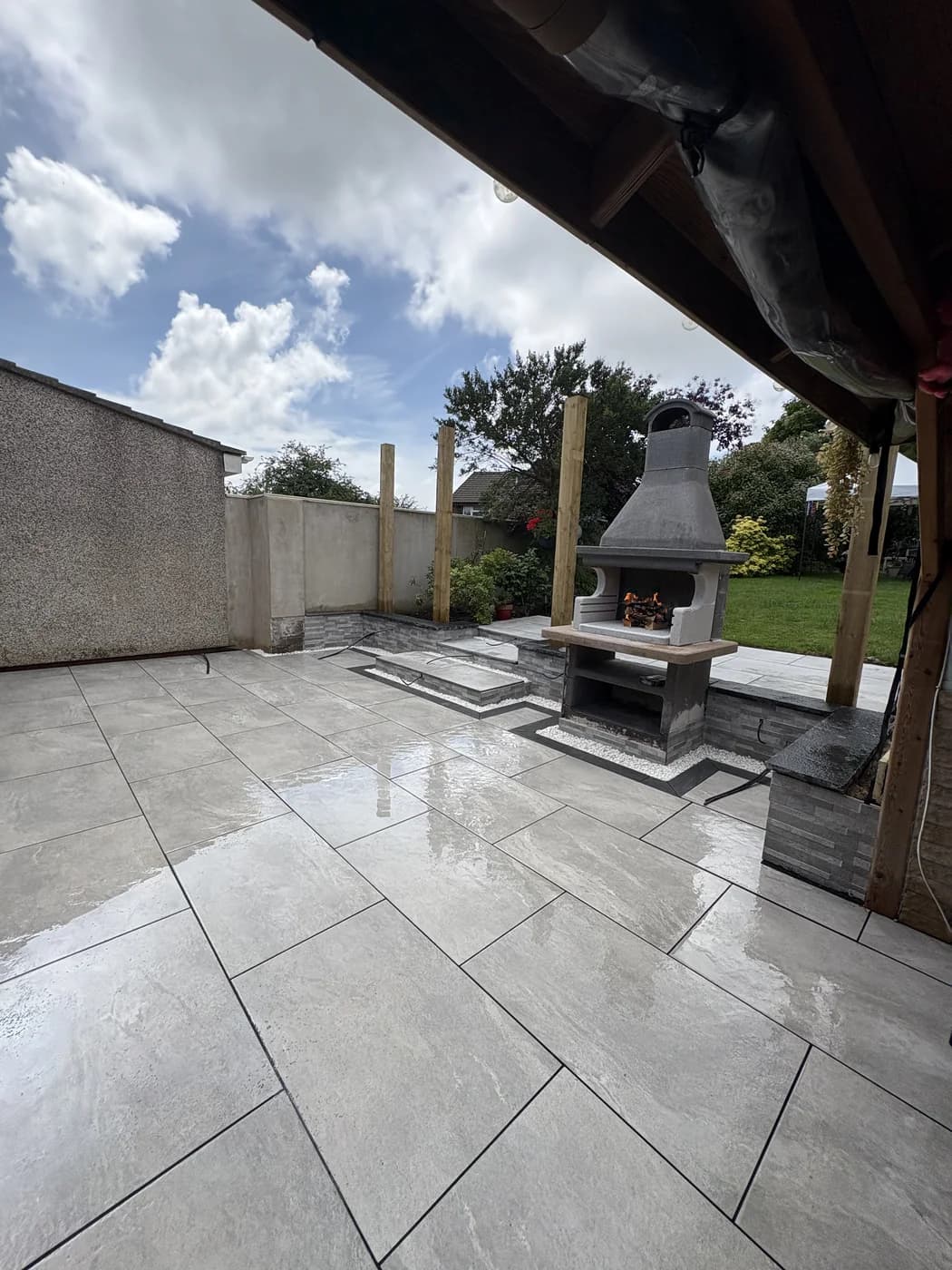 Covered pergola with an outdoor fireplace and patio in Cowbridge by HJB